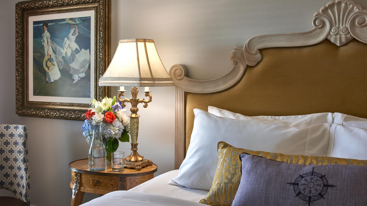 Close up of a bed, throw pillows, and a bedside table.