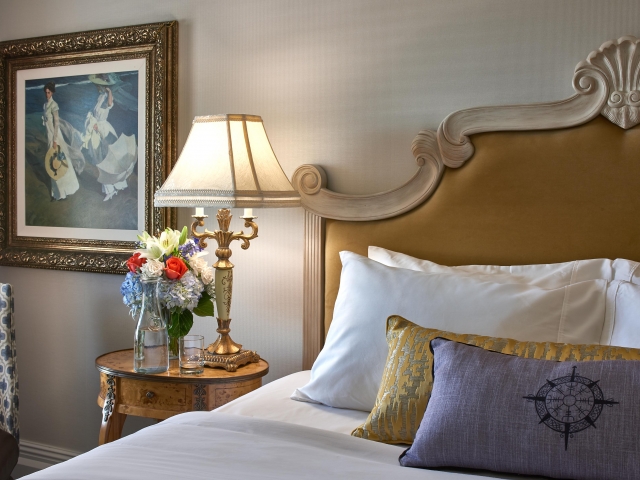 Close up of a bed, throw pillows, and a bedside table.