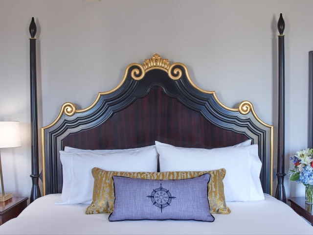Interior view of a suite bedroom with a decorative headboard and large king sized bed.