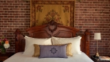 The headboard and brick wall of the Kingscote suite bedroom.