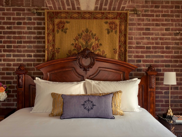 The headboard and brick wall of the Kingscote suite bedroom.