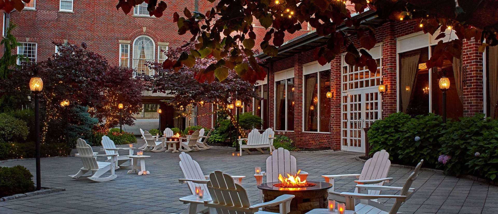 Courtyard with outdoor fireplaces and desk chairs at dusk
