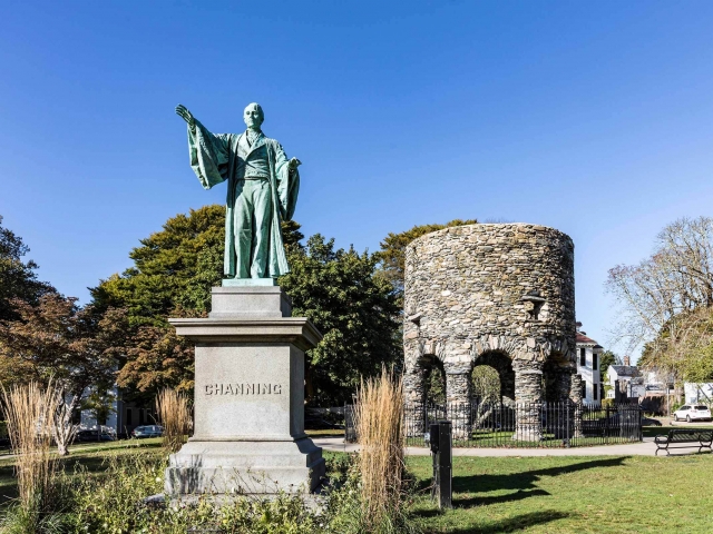 The Channing statue in a park with a circular stone tower in the background