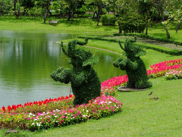 Animal topiaries on the edge of a pond in the shape of elephants