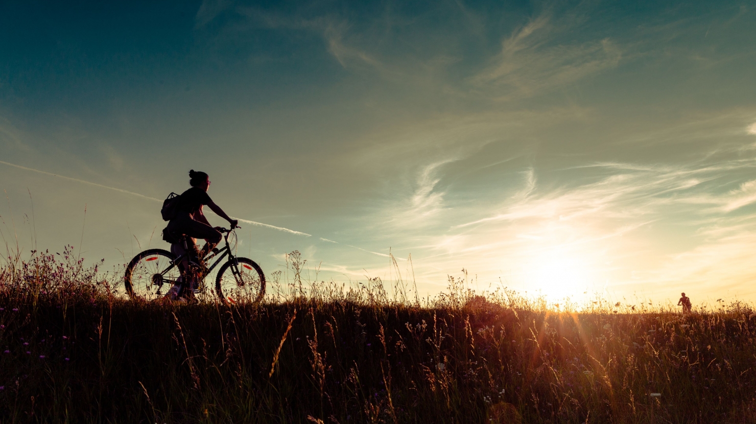 A woman cycling at sunset.